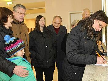 Irina Trukenbrod macht den Anfang und trägt sich auf der Unterschriftenliste ein. Mit im Bild ihre Tochter Lenya, ihre Eltern Ingrid und Klaus, Nadia Ramming, Karl Heinz Ramming und (verdeckt) Sabine Bredemeyer und Manfred Sallmann. Foto: Katrin Geyer