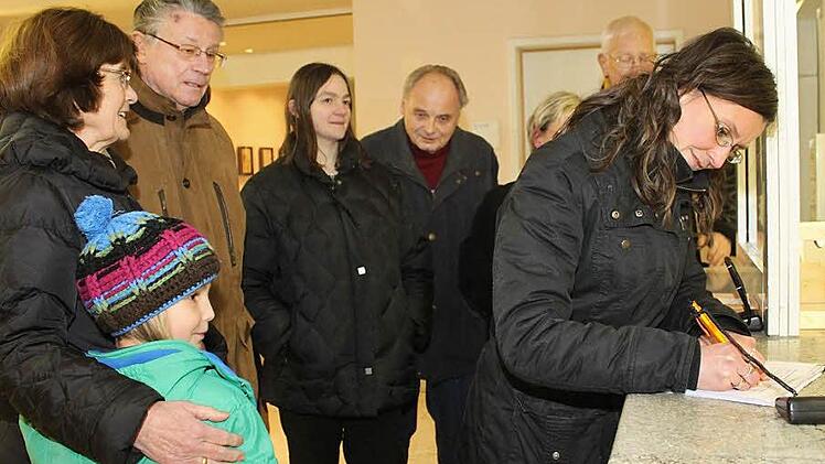 Irina Trukenbrod macht den Anfang und trägt sich auf der Unterschriftenliste ein. Mit im Bild ihre Tochter Lenya, ihre Eltern Ingrid und Klaus, Nadia Ramming, Karl Heinz Ramming und (verdeckt) Sabine Bredemeyer und Manfred Sallmann. Foto: Katrin Geyer