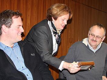 Bürgermeisterin Brigitte Meyerdierks überreicht Jochen Krug ein kleines Geschenk. Nachfolger und Sohn Michael Krug freut sich mit. Foto: Ulrike Müller