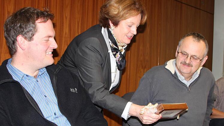 Bürgermeisterin Brigitte Meyerdierks überreicht Jochen Krug ein kleines Geschenk. Nachfolger und Sohn Michael Krug freut sich mit. Foto: Ulrike Müller