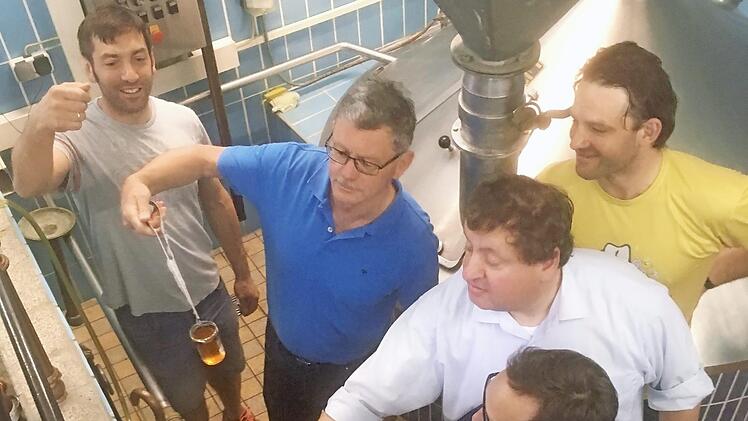 Litzendorfs Bürgermeister Wolfgang Möhrlein (im blauen T-Shirt) beim Bierbrauen in der ehemaligen Brauerei Winkler in Melkendorf. Es wird gerade vom Team um Braumeister Christian Grasser (im gelben T-Shirt) die Vorderwürze begutachtet, die vom Läuterbottich in die Kochpfanne gepumpt wird, um anschließend mit Hopfen versehen, aufgekocht wird. Foto: Andrea Spörlein
