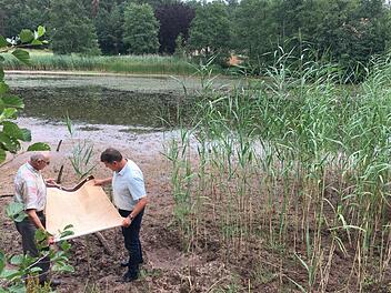 Georg Rebhan (links) zeigt  Bürgermeister  Carsten Joneitis eine historische Karte, auf der die Seen bei Sandhof eingezeichnet waren. Beide stehen auf dem Grund des Oberen Haussees, den  es so bald nicht mehr geben könnte, weil das Wasser fehlt. Foto:  Anette Schreiber