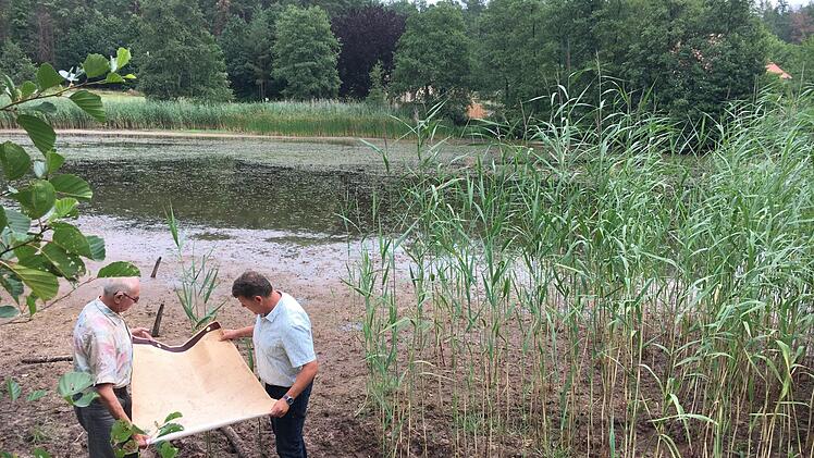 Georg Rebhan (links) zeigt  Bürgermeister  Carsten Joneitis eine historische Karte, auf der die Seen bei Sandhof eingezeichnet waren. Beide stehen auf dem Grund des Oberen Haussees, den  es so bald nicht mehr geben könnte, weil das Wasser fehlt. Foto:  Anette Schreiber