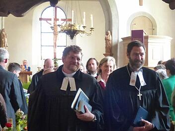 Nach dem Festgottesdienst in der Heilig-Kreuz-Kirche in Holzhausen schreiten Dekan Jürgen Blechschmidt (rechts) und der neu ins Amt eingeführte Pfarrer Mátyás Beke aus dem Gotteshaus. Foto: Manfred Wagner