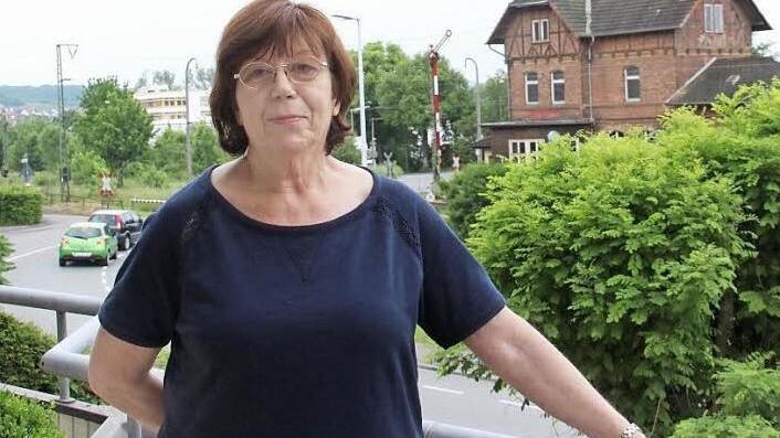 Ursula Fehling auf ihrem Balkon. Im Hintergrund rechts ist das denkmalgeschützte Creidlitzer Bahnhofsgebäude zu sehen, links der gerade mal wieder geschlossene Bahnübergang.  Foto: Simone Bastian