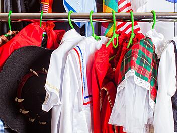 Ein bunter Kleiderständer voller Faschingskostüme in verschiedenen Farben, darunter rote, karierte und gestreifte Muster, erinnert an das traditionelle "Kaufhaus der fünf Jahreszeiten".