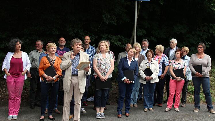 Mit der Benennung eines Weges im Pfarrschrot ehrte die Gemeinde Niederfüllbach am Samstag ihren verstorbenen Ehrenbürger Franz Möckl. "Würde man all seine Kompositionen und Liedblätter aneinanderlegen, wäre dieser Weg viel zu kurz", meinte Knut Gramß (Heldritt, vorn), der fast sechs Jahrzehnte lang Zeuge von Möckls Schaffen war. Die Einweihung wurde untermalt von Liedern des Komponisten, vorgetragen vom Singverein Niederfüllbach (Leitung Carolin Heckel, links), den Möckl viele Jahre geleitet ...