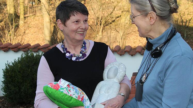 Doris Wienke (links) im Gespräch mit Cecilia Trautner. In der einen Hand hält sie die steinerne "Bürgerwilma", in der anderen eines ihrer gequilteten Herzkissen.  Foto: Christian Bauriedel