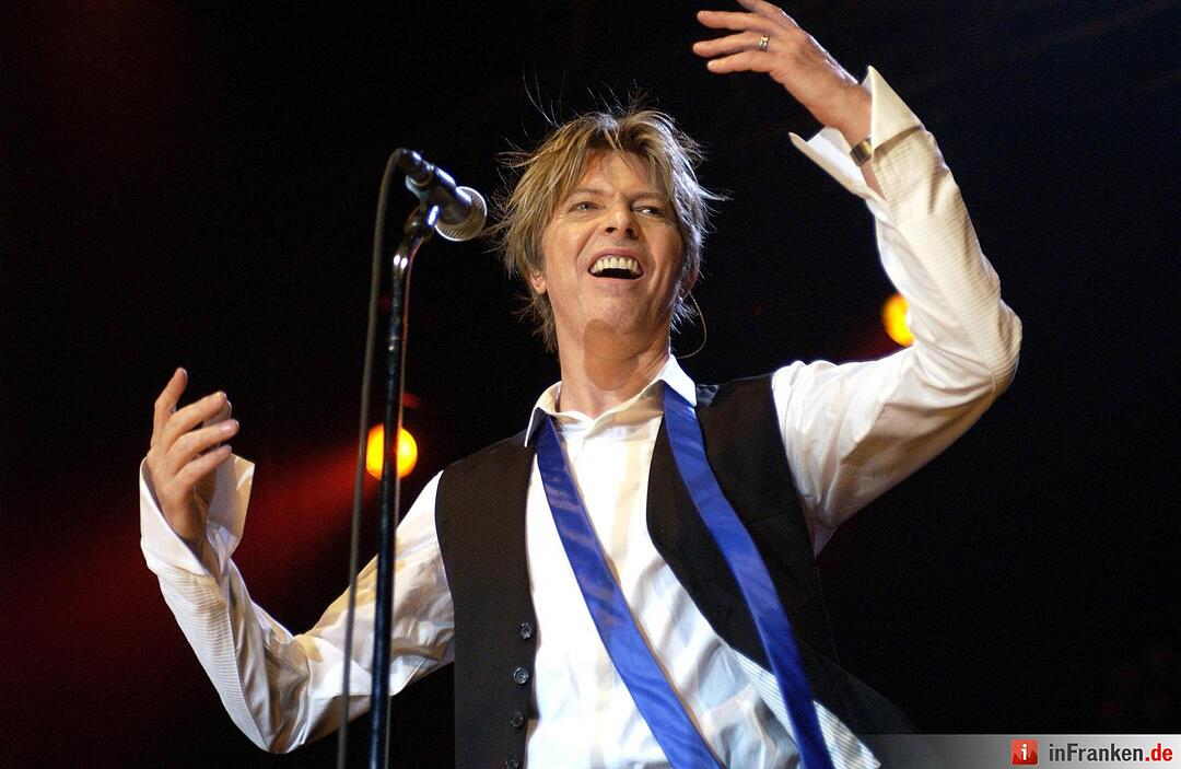 Mit einer Geste, die zum Mitfeiern auffordert, beginnt der britische Rockmusiker David Bowie am 12.07.2002 im Kölner E-Werk sein viel umjubeltes Deutschland-Konzert. Foto: Jörg Carstensen/dpa