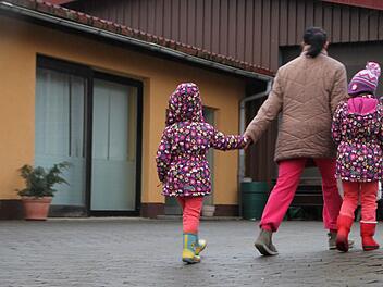Eine Bewohnerin läuft mit ihren Kindern über den Hof der Flüchtlingsunterkunft in Schondra.  Foto: Ulrike Müller