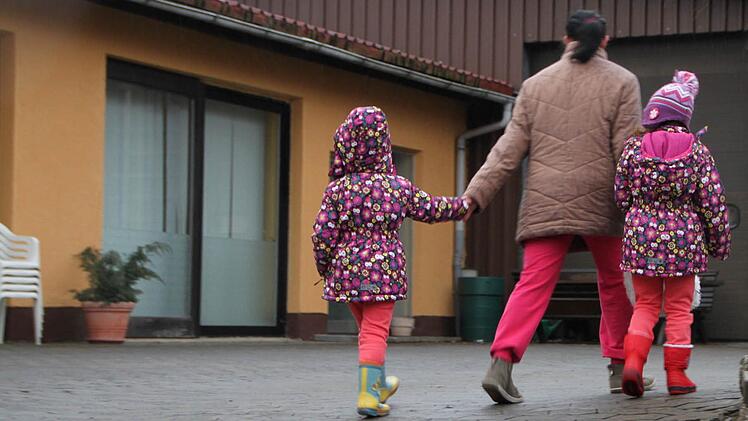 Eine Bewohnerin läuft mit ihren Kindern über den Hof der Flüchtlingsunterkunft in Schondra.  Foto: Ulrike Müller