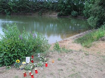 Kerzen und Blumen am Kleinsendelbacher See, in dem der kleine Junge gefunden wurde. Foto: Martin Rehm