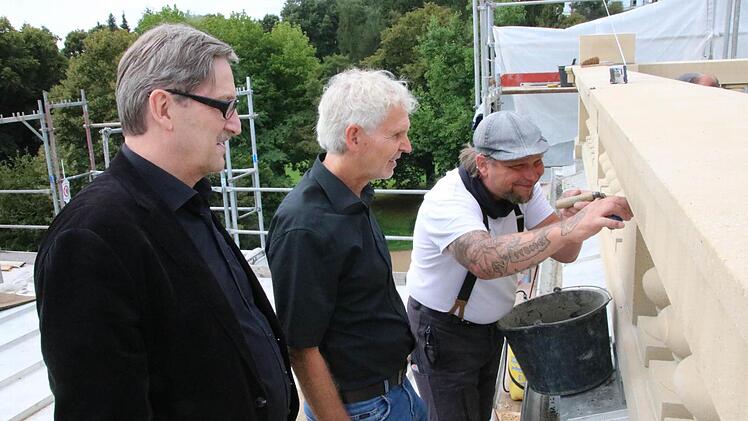 Otto Gass (von links) und Erwin Full vom Staatlichen Bauamt schauen auf dem Dach Steinmetz Steven Müller beim Verfugen der Balustraden auf dem Luitpoldbad über die Schulter. Fotos: Ralf Ruppert