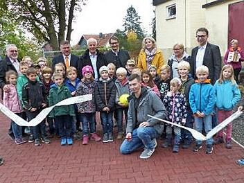 Tobias Lamnek (hockend, Bildmitte) war es vorbehalten, mit dem Durchschneiden eines Bandes den neugestalteten Pausenhof offiziell freizugeben. Foto: Klaus-Peter Wulf