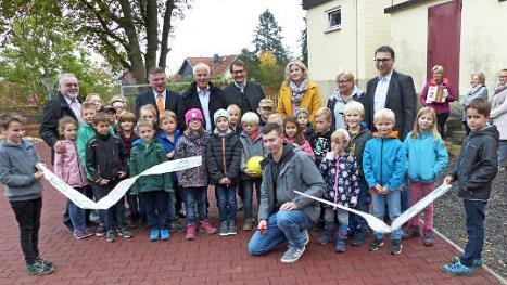Tobias Lamnek (hockend, Bildmitte) war es vorbehalten, mit dem Durchschneiden eines Bandes den neugestalteten Pausenhof offiziell freizugeben. Foto: Klaus-Peter Wulf