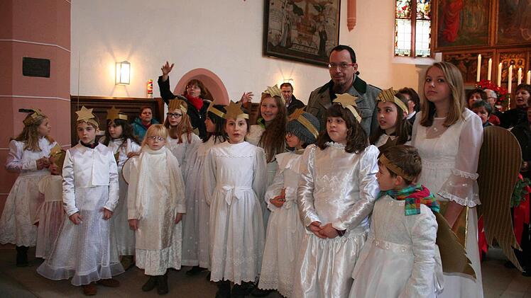 Chorleiter Ingrid Geyer (im Hintergrund) gab die Einsätze für den Kanon. Rechts im Bild das Christkind, die 14-jährige Mia Bader