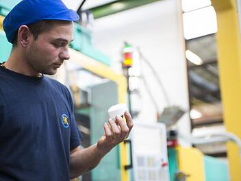 Cremetiegel und andere Kosmetikverpackungen werden bei Hermann Koch hergestellt. Alexander Kibe mit einem Spritzgussdeckel. Foto: Hermann Koch GmbH