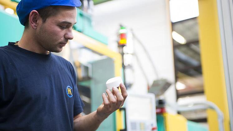 Cremetiegel und andere Kosmetikverpackungen werden bei Hermann Koch hergestellt. Alexander Kibe mit einem Spritzgussdeckel. Foto: Hermann Koch GmbH