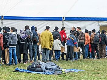 Zahlreiche Flüchtlinge warteten auch am Mittwoch wieder an der deutsch-österreichischen Grenze vor einem Zelt. Der Flüchtlingsstrom hält ungehindert an.  Foto: Armin Weigel (dpa)