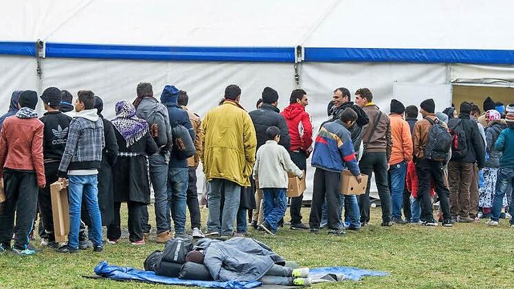 Zahlreiche Flüchtlinge warteten auch am Mittwoch wieder an der deutsch-österreichischen Grenze vor einem Zelt. Der Flüchtlingsstrom hält ungehindert an.  Foto: Armin Weigel (dpa)