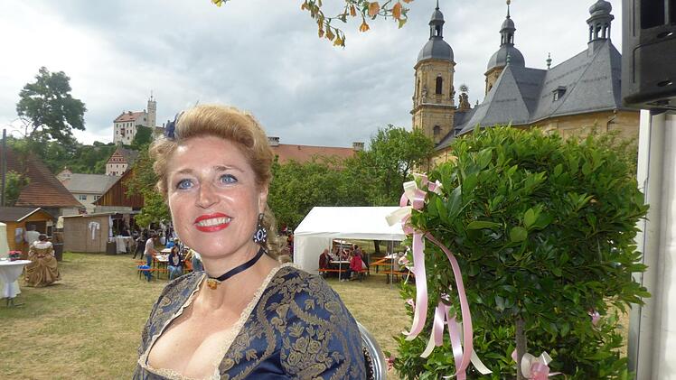 Organisatorin Daniela Drummer im Pfarrgarten  mit Burg uned Basilika im Hintergrund.
