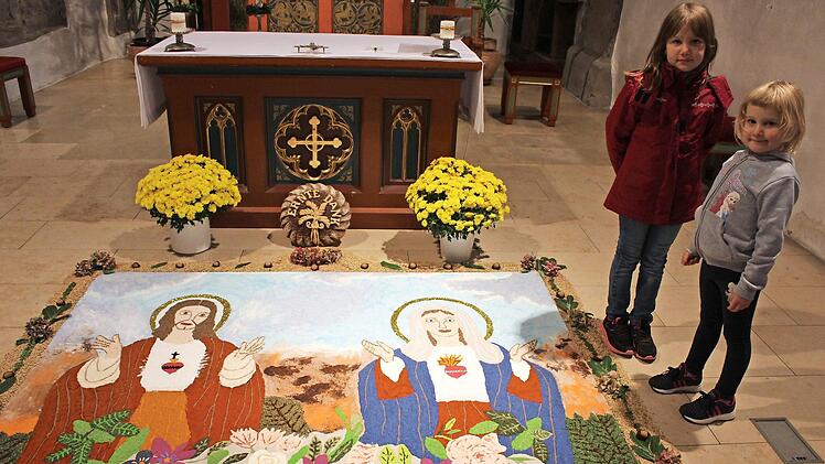 "Herz Jesu und Herz Mariens" ist der Titel des Andachtbildes, das bis Allerheiligen in der Kirche zu besichtigen ist. Die siebenjährige Eva und die fünfjährige Lena wurden schon in die Tradition eingebunden  Fotos: Seeger
