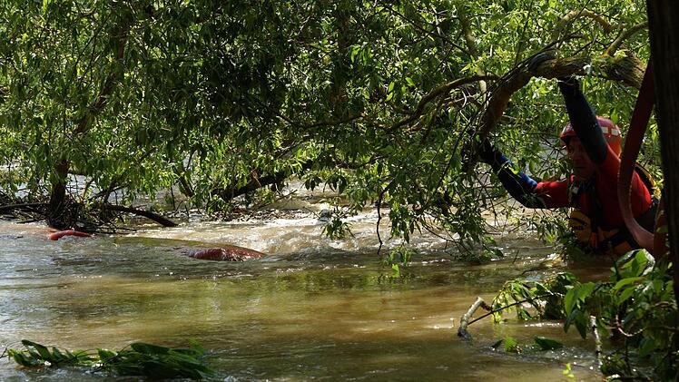 Ein Wasserwachtler versucht ans gekenterte Boot zu kommen.