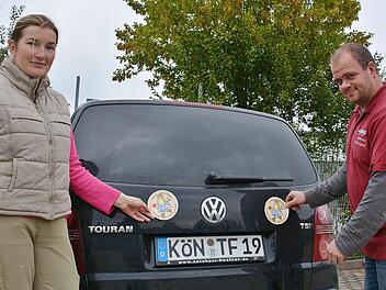 Andrea Friedrich-Rückert (Foto Engele) und Florian Guck (Landfuxx Guck) präsentieren den neuen Autoaufkleber, der nun in den verschiedenen Geschäften erhältlich ist. 50 Cent der drei Euro gehen an das Projekt "Kinderhäuser" im Kinderland Bad Königshofen. Foto: Friedrich