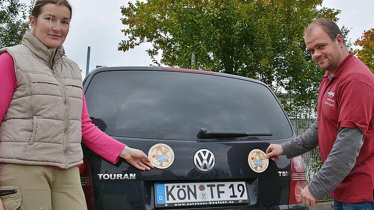 Andrea Friedrich-Rückert (Foto Engele) und Florian Guck (Landfuxx Guck) präsentieren den neuen Autoaufkleber, der nun in den verschiedenen Geschäften erhältlich ist. 50 Cent der drei Euro gehen an das Projekt "Kinderhäuser" im Kinderland Bad Königshofen. Foto: Friedrich