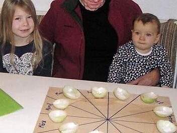 Mit Spannung erwartet Kurt Markert das Ergebnis seines Zwiebelorakels am Neujahrsabend. Gesellschaft leisten im seine Enkelinnen Marie (links) und Lina Zenk (rechts).