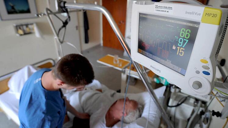 Ein Krankenpfleger überprüft die Messinstrumente bei einem Schlaganfallpatienten.  Archiv/Angelika Warmuth, dpa