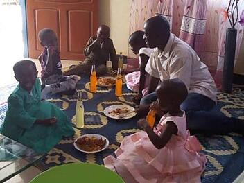 Der Arzt Martine Mwampamba mit seinen Kindern und deren Freunden aus der Nachbarschaft beim Weihnachtessen: Reis, Fleisch und Limonade. So ähnlich wird auch das Festmahl an Silvester aussehen.  Foto: Kivuko