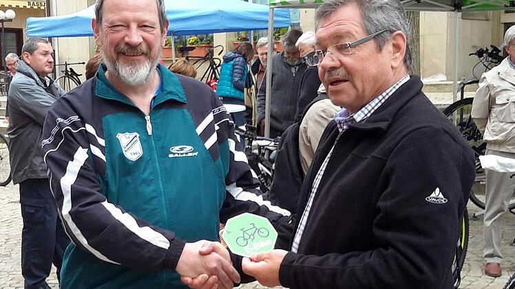 Symbolischer Akt: Forums-Vorsitzender Hans Rohrmüller (rechts) übergibt das erste Hinweisschild auf die Ladestationen an Erwin Miller vom SV Römershag. Foto: Rolf Pralle