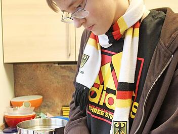Julian legt die Kartoffscheiben in die Auflaufform.
