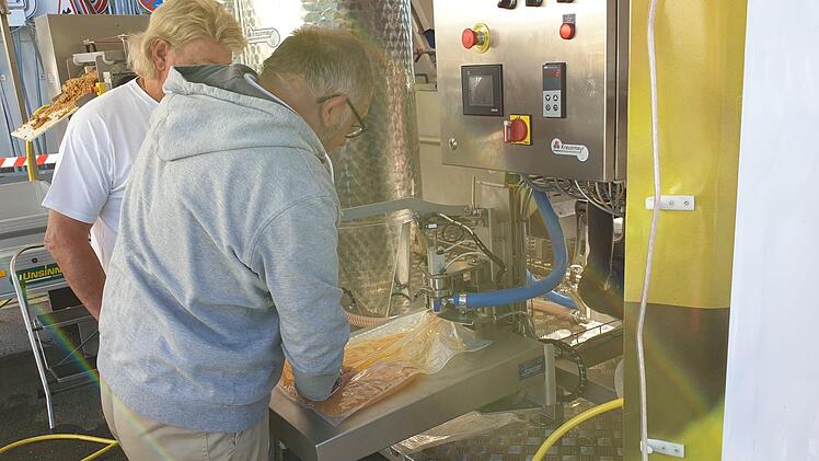 Die ehrenamtlichen Bediener der Anlage füllen den erhitzten Saft in Vakuumbeutel mit einem Inhalt von fünf  oder zehn  Litern und bereiten ihn für die Ausgabe an die Kunden vor. Foto: Martin Albert