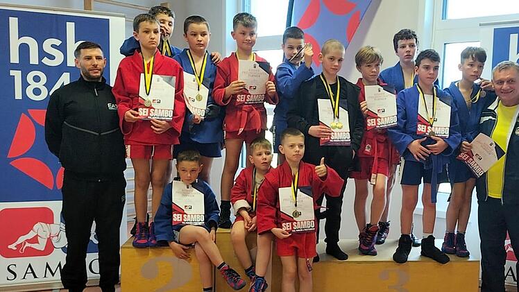 Unser Bild zeigt (hinten, von links) Sambo-Jugendtrainer Adam Köpplin, Roman Moskchaneiskij, Roman Gutwin, Artjom Moskchaneiskij, Daniel Strak, Adam Chrebtow, Pascal Rasvalaev, Viktor Balandin, Alessio Pizzutto, Elias Hensch, Robert Turanyi und Sambo-Trainer Albert Köpplin sowie (vorne, von links) Alexander Antoschkin, Johann Chrebtow und Wadim Vyhivskyi. Foto: privat