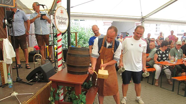 Bürgermeister Johannes Krumm (Mitte) gelang sein erster Bieranstich beim zweiten Schlag. Gemeinderat Tobias Warter (rechts) wartet bereits mit den Freibier-Krügen.