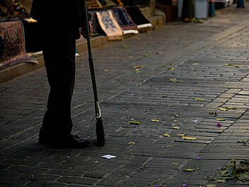 Ein Mann fegt eine Stra&szlig;e vor einer Kneipe in Erlagen und wird angegriffen
