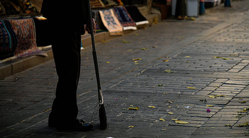 Ein Mann fegt eine Stra&szlig;e vor einer Kneipe in Erlagen und wird angegriffen