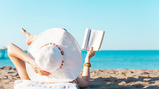 Frau liest im Urlaub am Strand