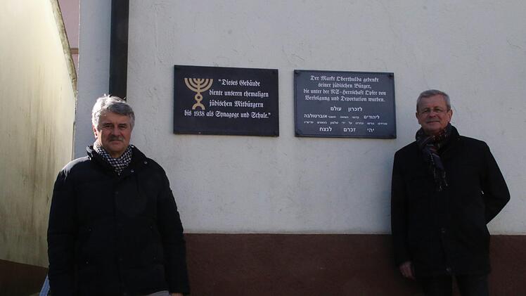 Klaus Blum und Bürgermeister Gotthard Schlereth am Platz wo der Rucksack auf einem Sockel aus Holz und Eisenbahnschiene unter der Tafel seinen Platz finden soll.