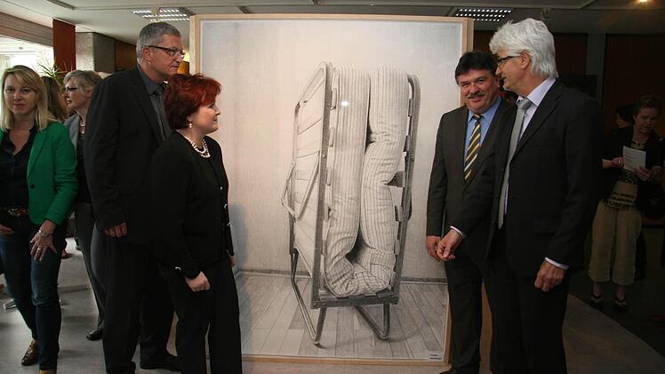 Das Klappbett symbolisiert, dass Menschen Fremde beherbergen sollen. Stellvertretende Landrätin Christina Flauder, Günter Breitenbach von der Rummelsberger Diakonie, Landrat Klaus Peter Söllner und Fritz Glock (von links) bestaunen das Kunstwerk von Martin Schmidt. Foto: Sonja Adam