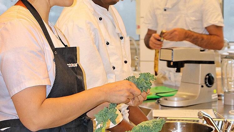 Die Blatt-Rippen des Grünkohls müssen vor dem Blanchieren entfernt werden. Lehrerin Katharina Zeller zeigt, wie das funktioniert. Foto: Dieter Britz