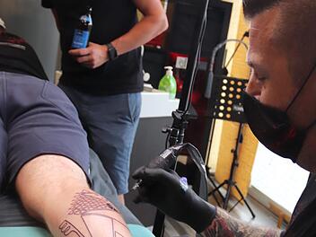 Sponsor Hans-Günter Wirth (Mitte) beobachtet wie Marcus Fleischmann das Tattoo sticht.  Foto: Johanna Blum
