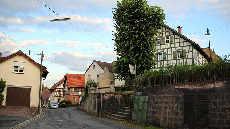 Im Zuge des Ausbaus der Bergstraße in Autenhausen lässt das Landratsamt auf Höhe der Kirche eine neue Stützmauer errichten. Für diese müssen das Kriegerdenkmal versetzt und die Linde gefällt werden, informierten die Verantwortlichen bei einer Bürgerversammlung im Sportheim. Weil ein Gehweg die Verkehrssicherheit in der Engstelle verbessern soll, wird zukünftig eine Ampel den Begegnungsverkehr dort auf ein Minimum reduzieren. Foto: Bettina Knauth