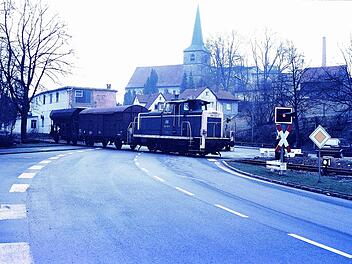 Die Baureihe V 100 zieht zwei Güterwägen über die Bundesstraße in Weißenbrunn. Heute sind die Gleise dort abgebaut.   Foto: Rolf Schierer