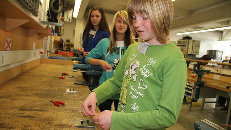 Lara Lippmann (11), Silke Herrmann (12) und Marie Moritz (13) probieren biegen bei Glen Dimplex Geduldsspiele aus Draht.