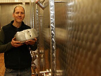 Thomas Lange zeigt den CD-Player in der Kelterhalle. Das Gerät ist auf einem Hocker bei den Gärtanks aufgebaut. Foto: Arkadius Guzy