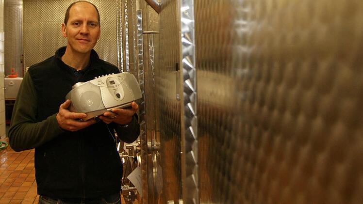 Thomas Lange zeigt den CD-Player in der Kelterhalle. Das Gerät ist auf einem Hocker bei den Gärtanks aufgebaut. Foto: Arkadius Guzy