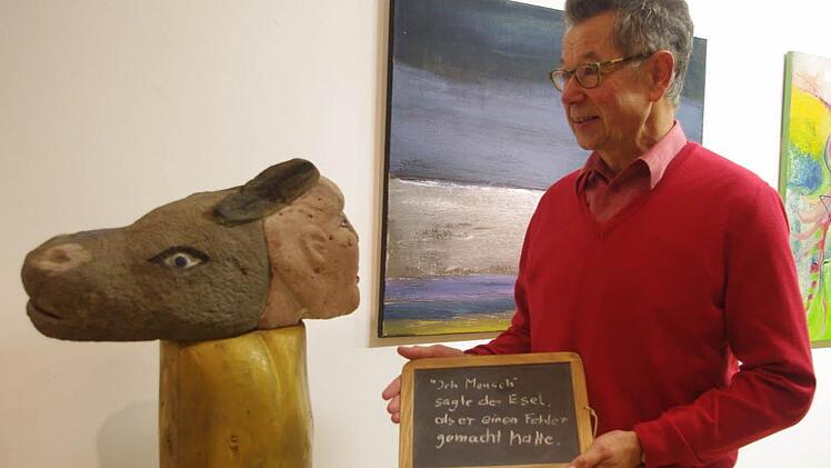 Gottfried Grau zeigt sein Kunstwerk aus rotem Sandstein mit dem Titel "Mensch und Esel".
